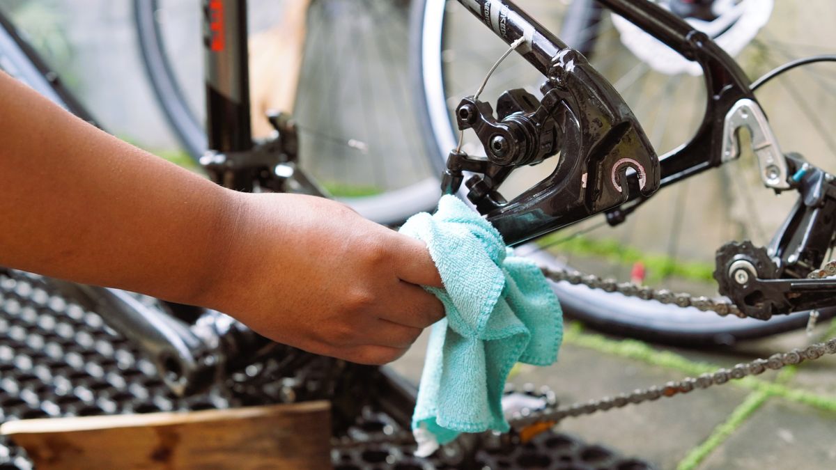 布で自転車のチェーンまわりを拭いて手入れをする手元