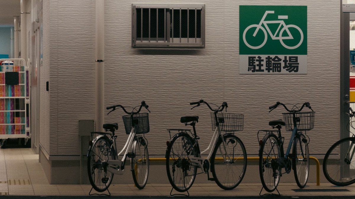 駐輪場の看板の下に並んだ、かご付きの自転車